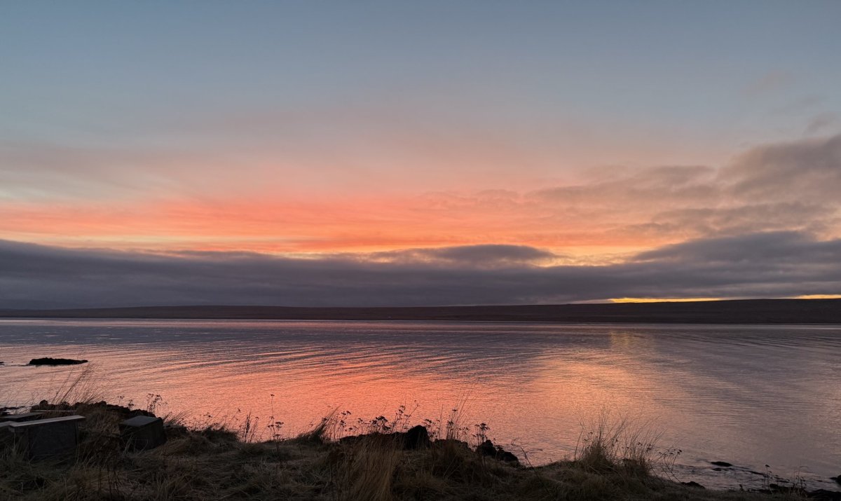 Blessuð nýárssólin séð af sjávarbakkanum við Bakkatún á nýársdag.